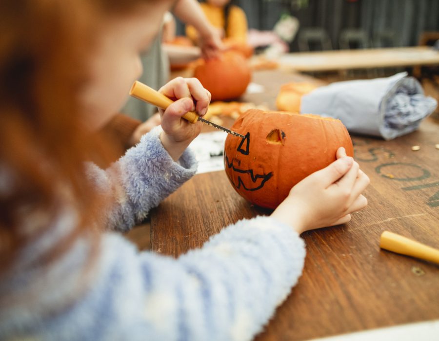 Family with children carving pumpkins at a farm after picking them at a farm in preparation for Halloween.